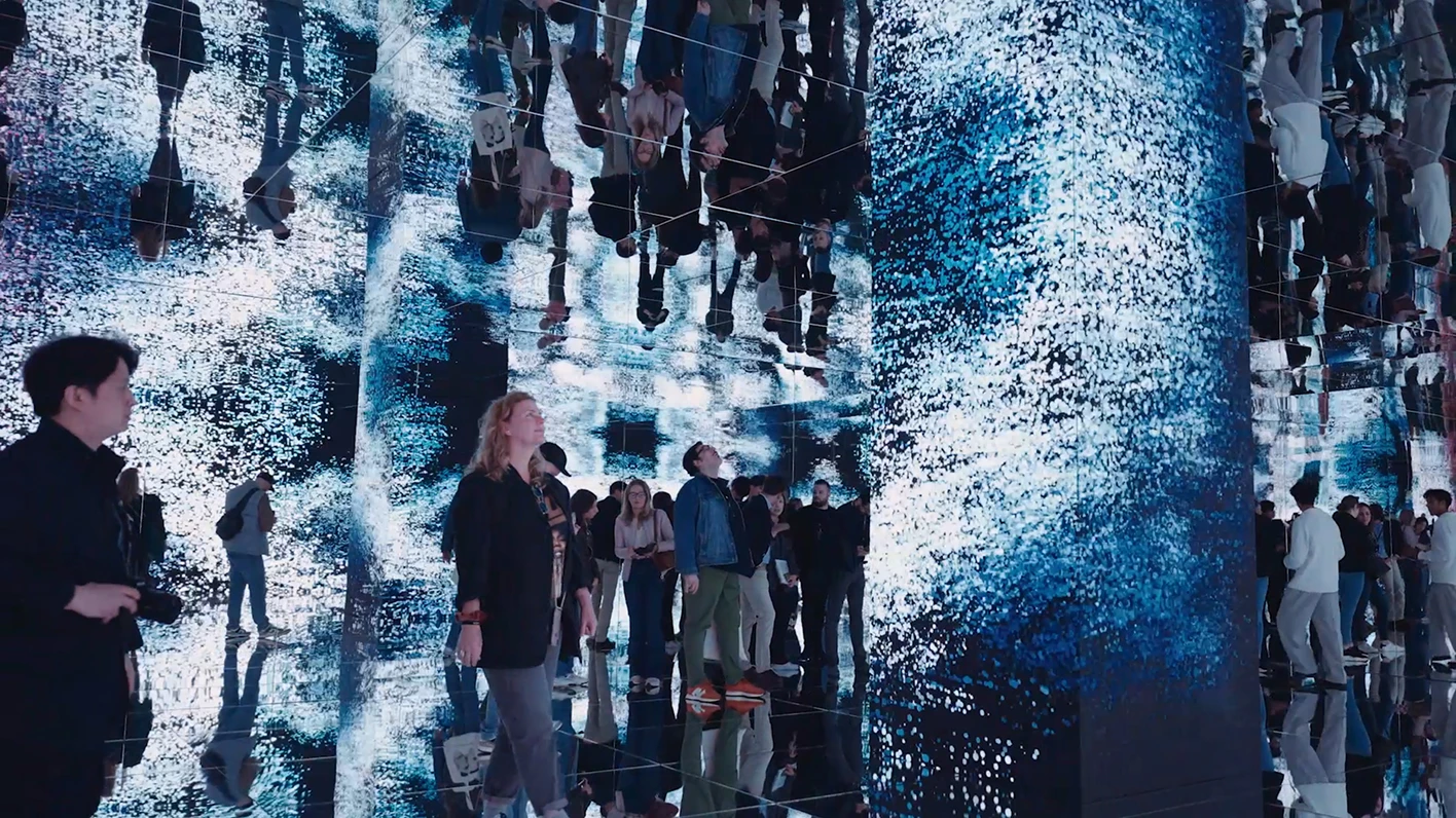 Visitors standing in front of a large media wall.