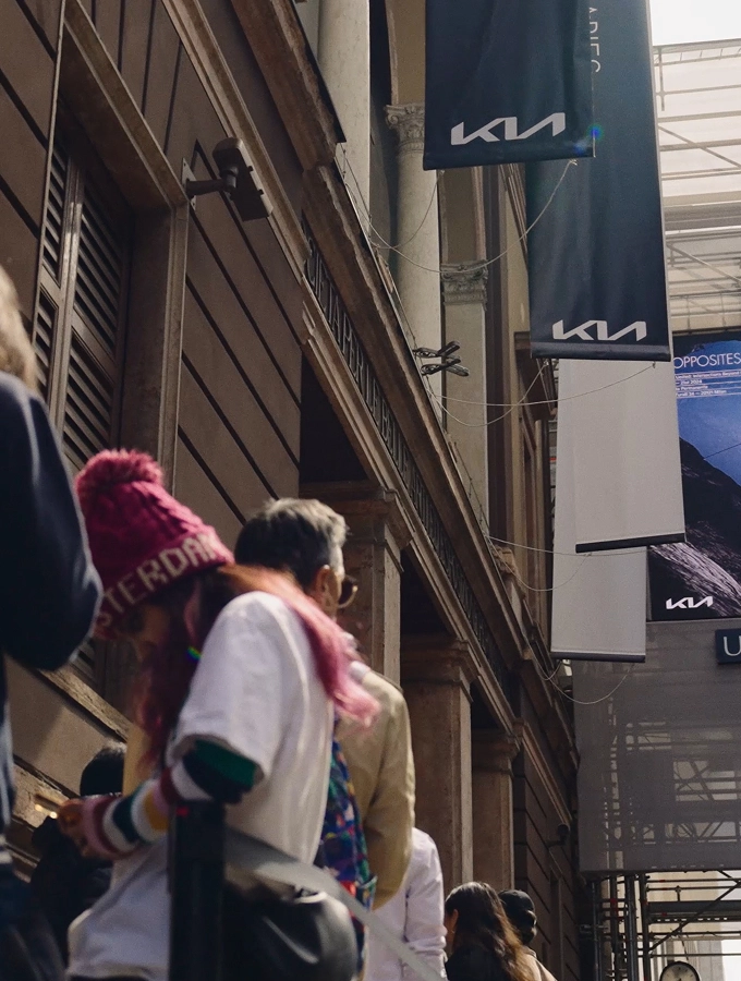 Kia logo flag on a building exterior and people walking along the street.