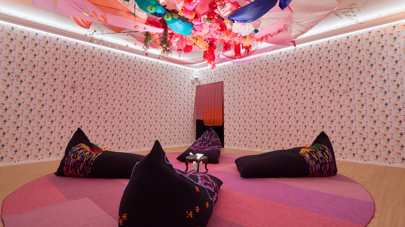 Exhibition interior with pink-toned installation and ceiling-hung elements from Anna Galtarossa’s ‘The Spirit of Disco.’