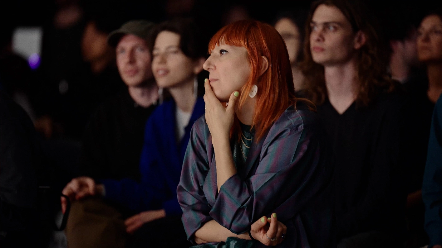 Anna Galtarossa seated in the audience, observing.