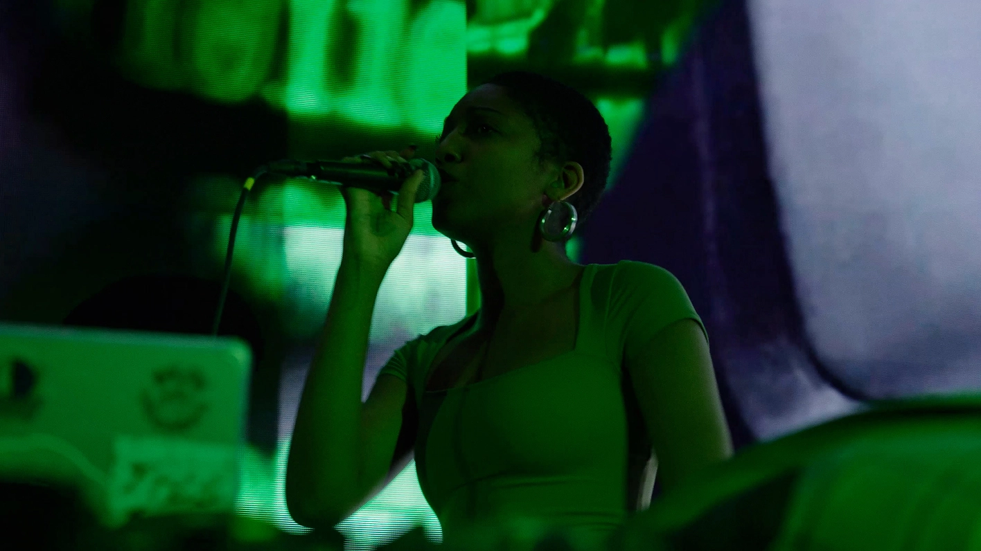 Artist XEXA singing under green lighting.