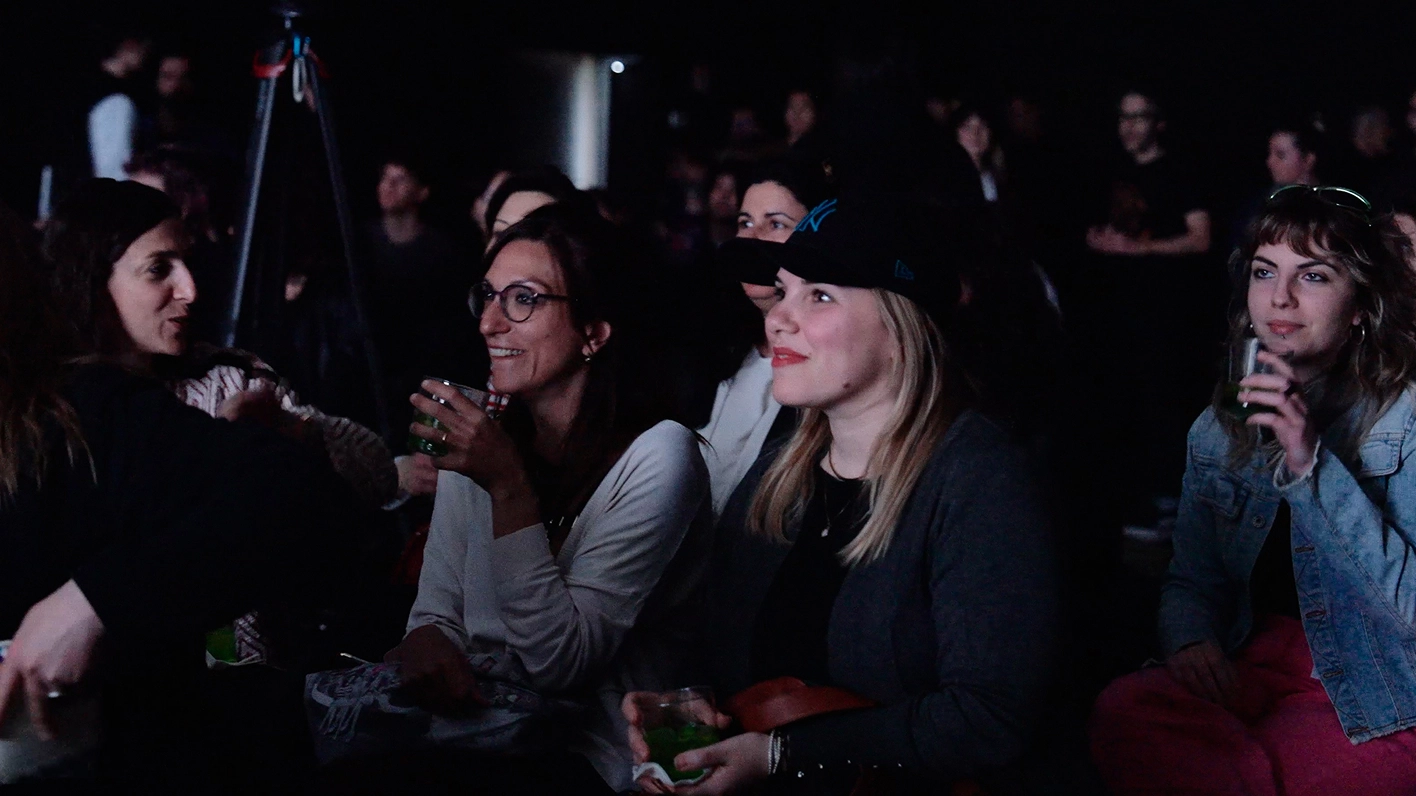 Audience watching the stage in a dark concert hall.
