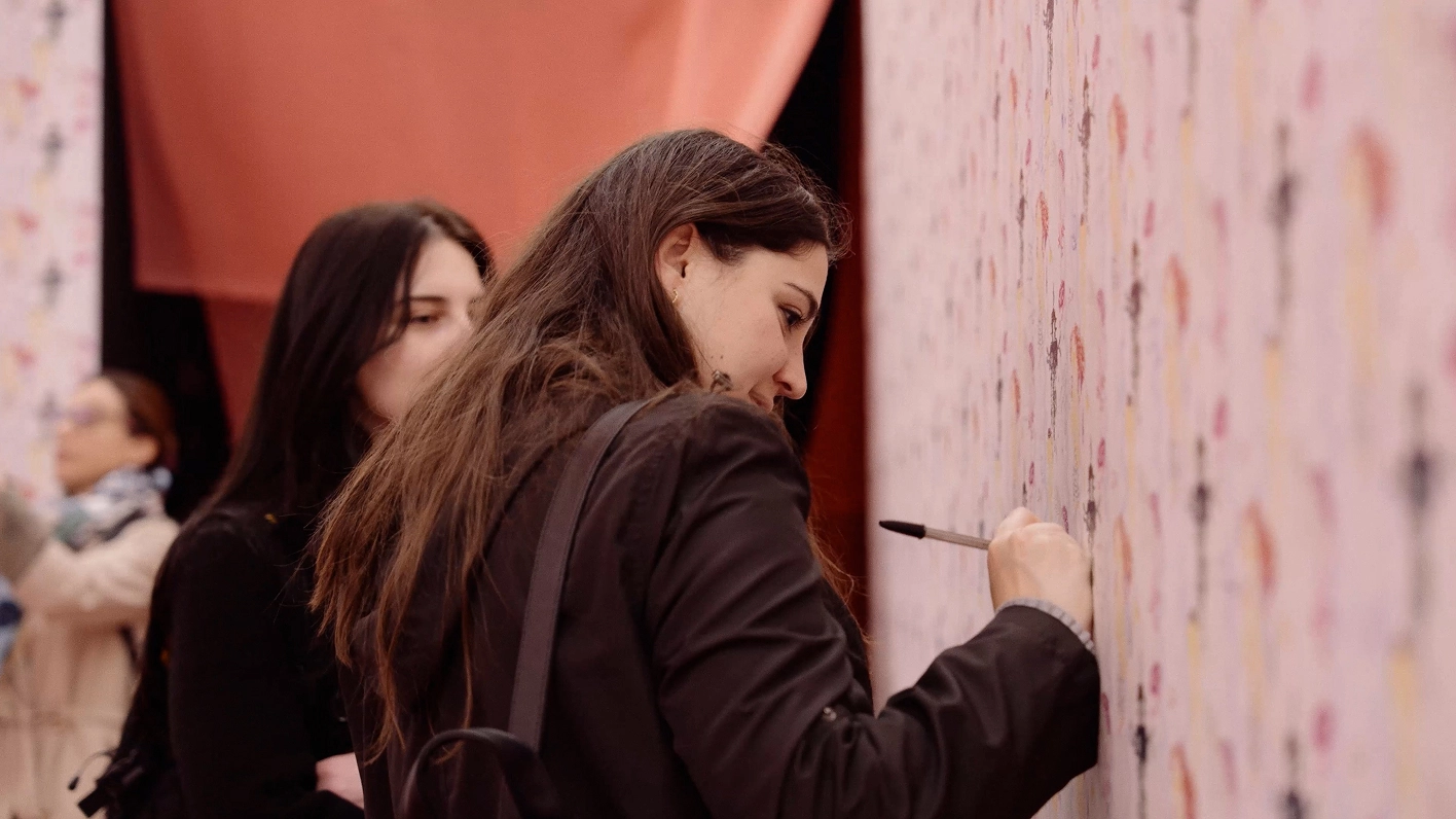 Female visitor writing on a wall.