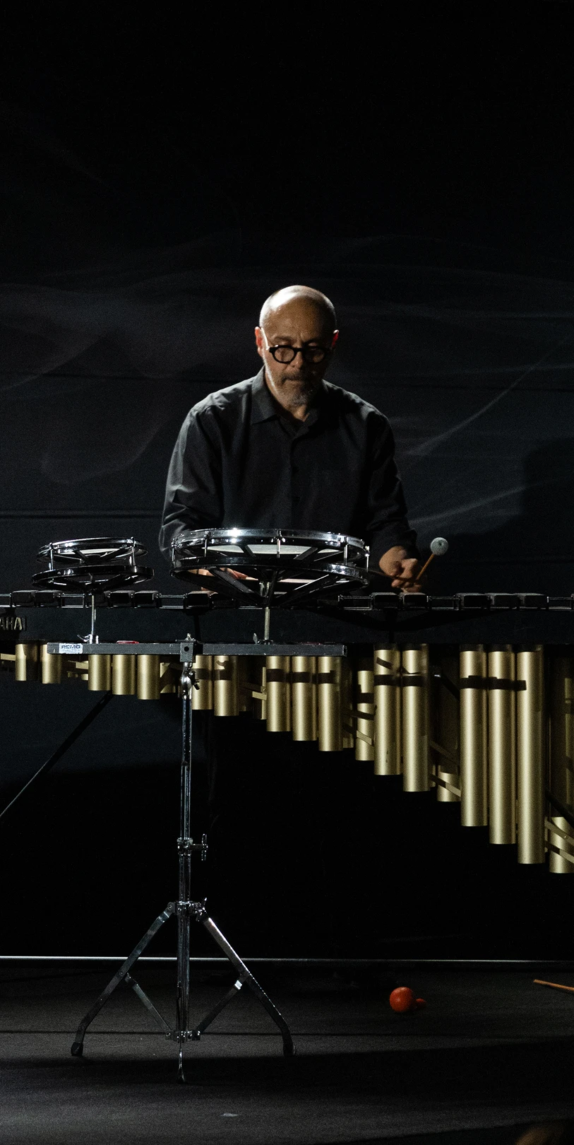 Musician Andrea Ceccarelli playing percussion on a dark stage.