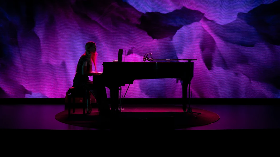 Silhouette of an artist playing the piano under purple lighting.