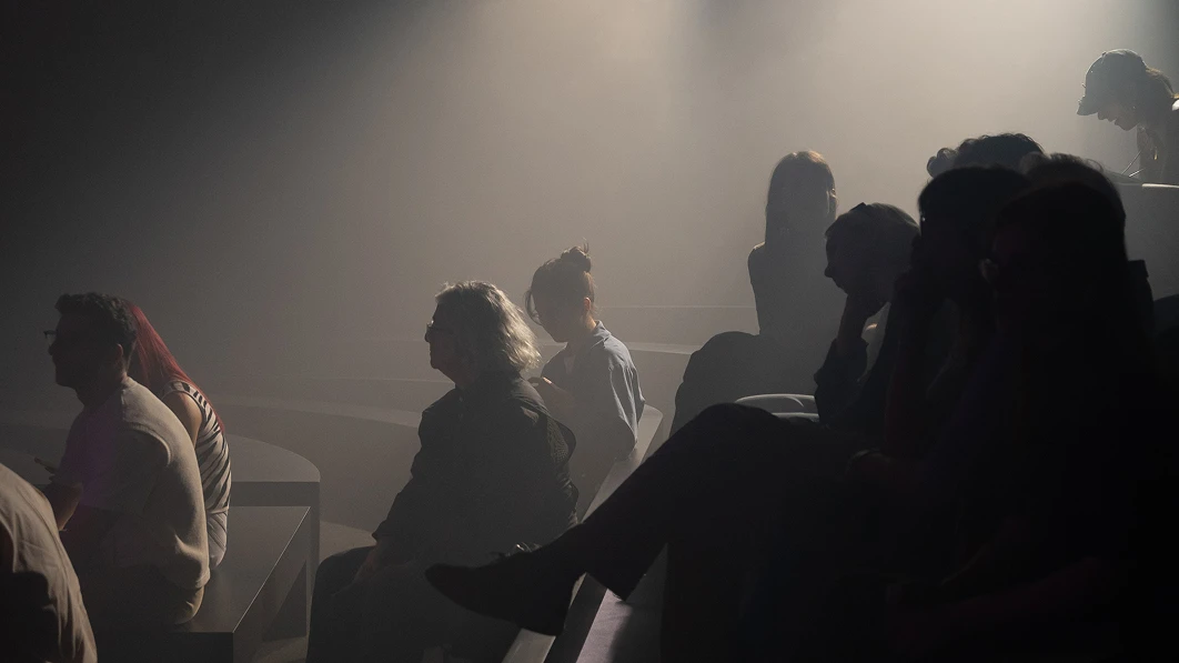 Audience silhouettes under stage lighting.