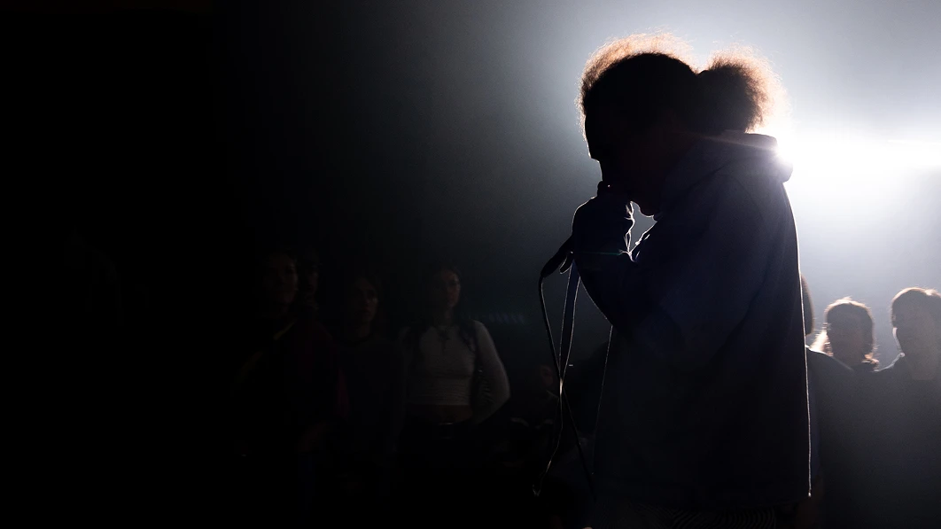 Silhouette of an artist singing with a microphone on stage.