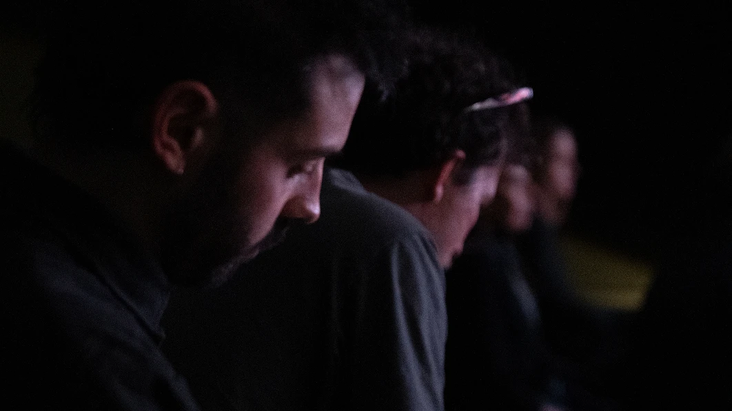Side view of audience members in a dark space.