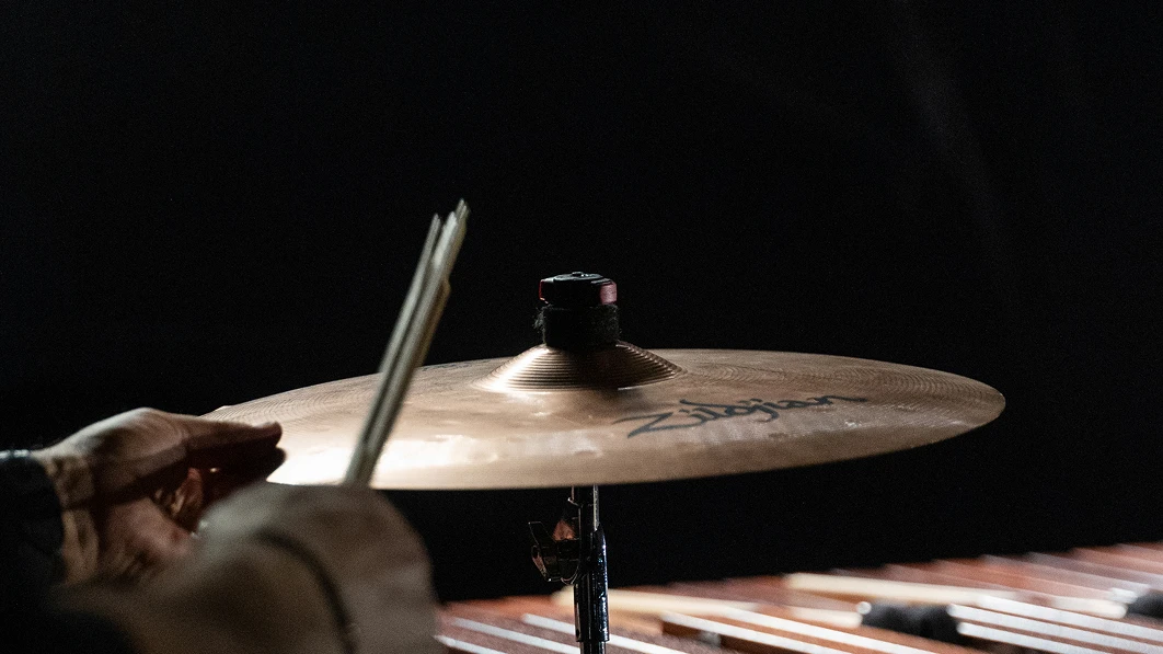 Close-up of hands playing a percussion cymbal.