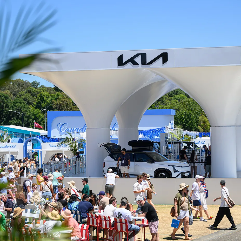 Image of visitors exploring a Kia vehicle and relaxing in front of a Kia brand booth at an outdoor event
