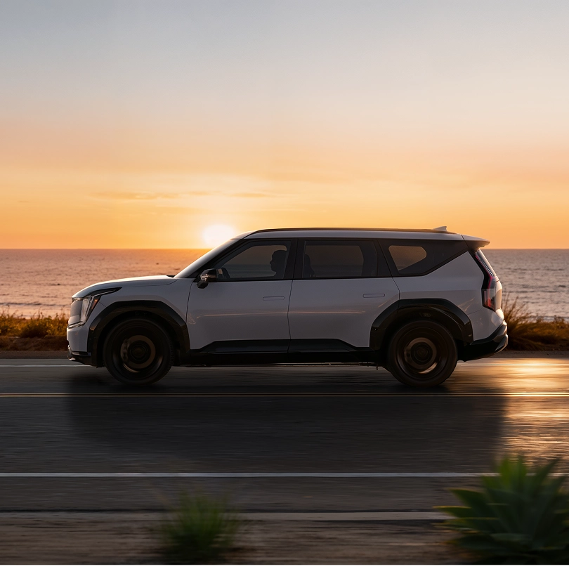 노을진 해안도로를 달리는 기아 SUV 이미지