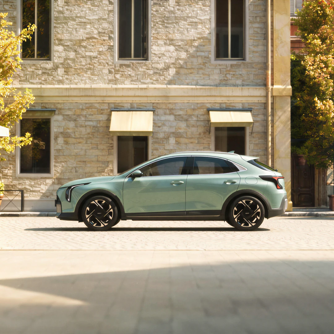 A mint-colored Kia vehicle parked in front of a stone building