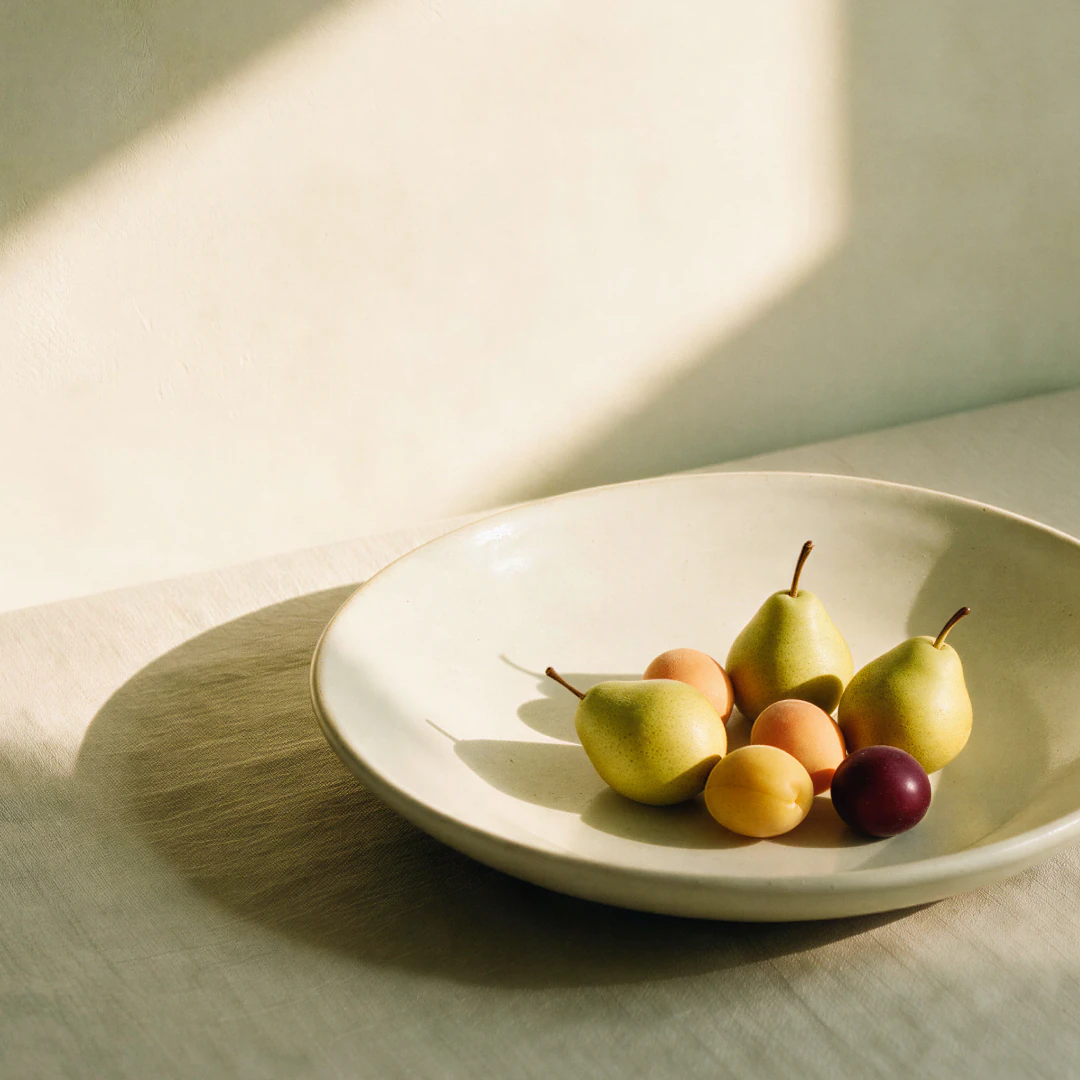 A plate of fruit on a sunlit table
