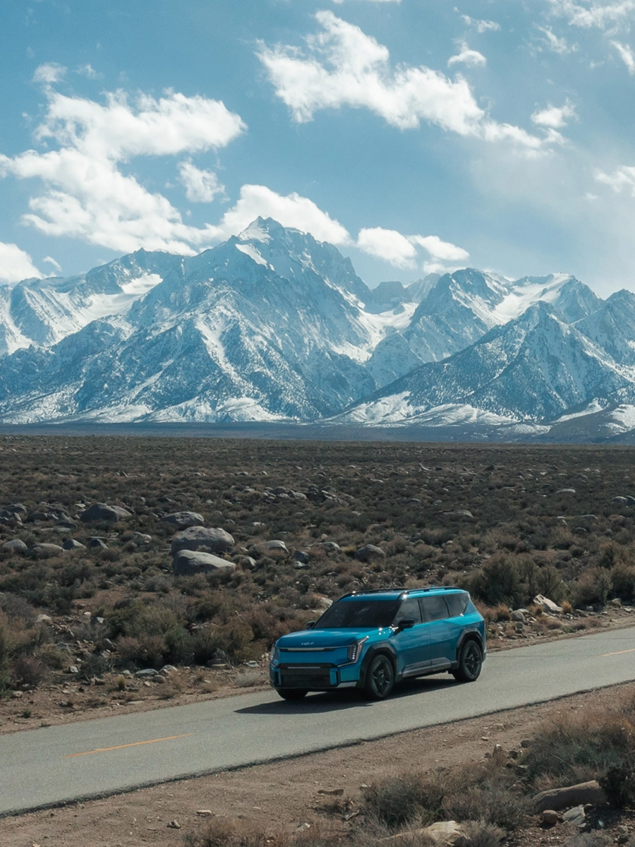 Kia EV9 driving on an open road through a vast natural landscape