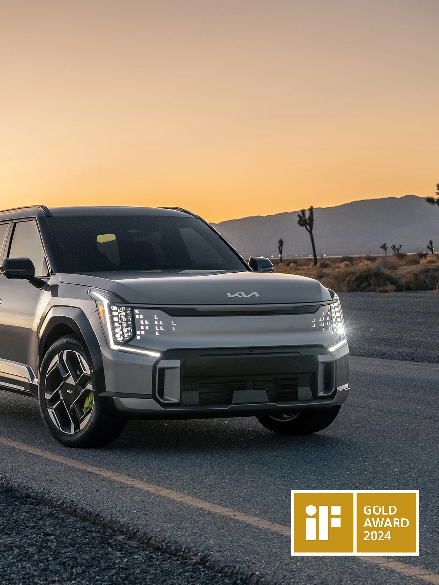 Front view of the Kia EV9 driving on a road at sunset
