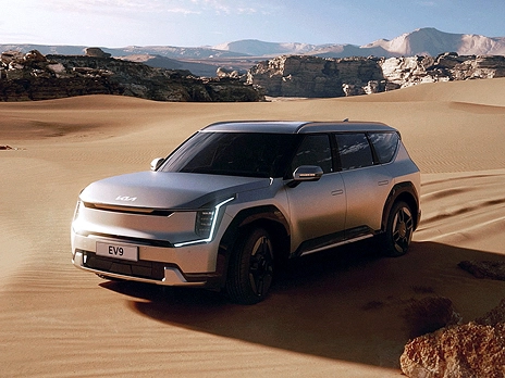 Front view of the Kia EV9 driving across a desert landscape