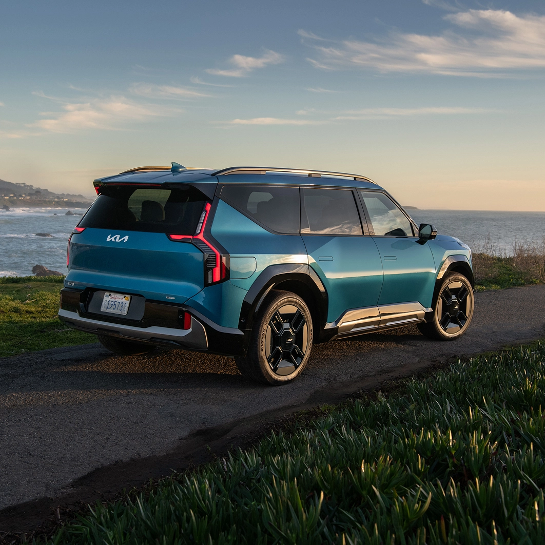 Rear and side view of the Kia EV9 parked by a coastal road