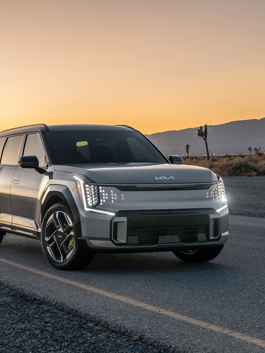 Front view of the Kia EV9 driving on a sunset road