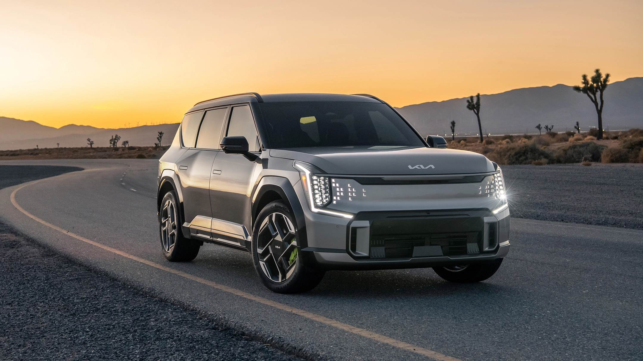 Front view of the Kia EV9 driving on a sunset road