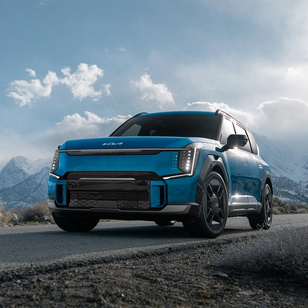 Front view of the Kia EV9 parked on a road with snow-covered mountains behind