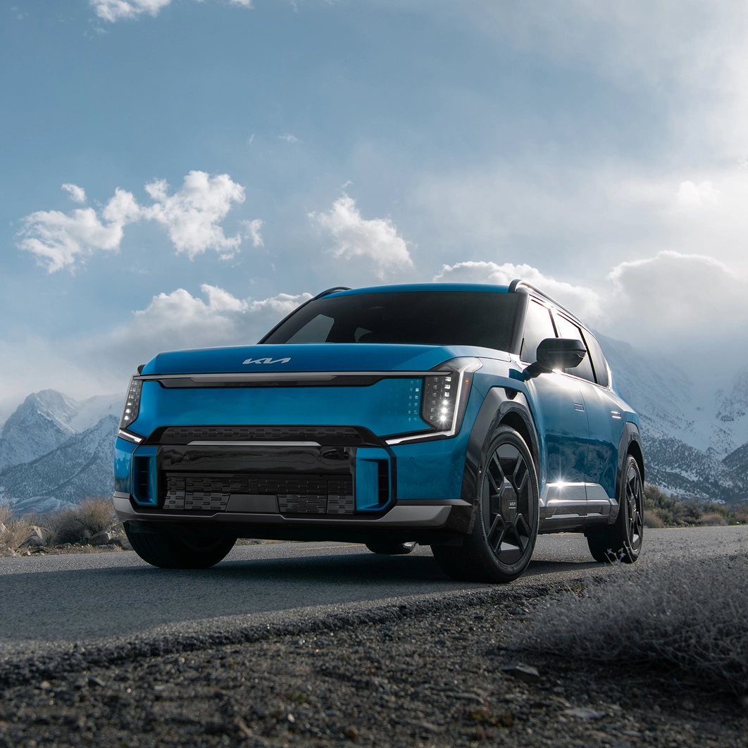 Front view of the Kia EV9 parked on a road with snow-covered mountains behind