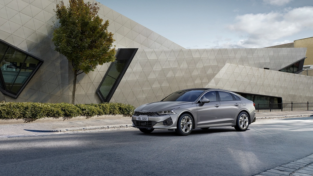 Kia K5 parked in front of a architectural building