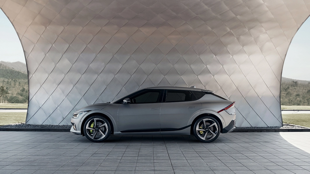 Side profile of the Kia EV6 GT parked beneath a curved architectural structure