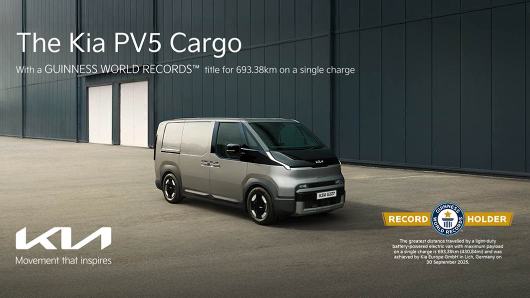 Front three-quarter exterior view of the Kia PV5 Cargo with “The Kia PV5 Cargo” and Guinness World Record driving range messaging