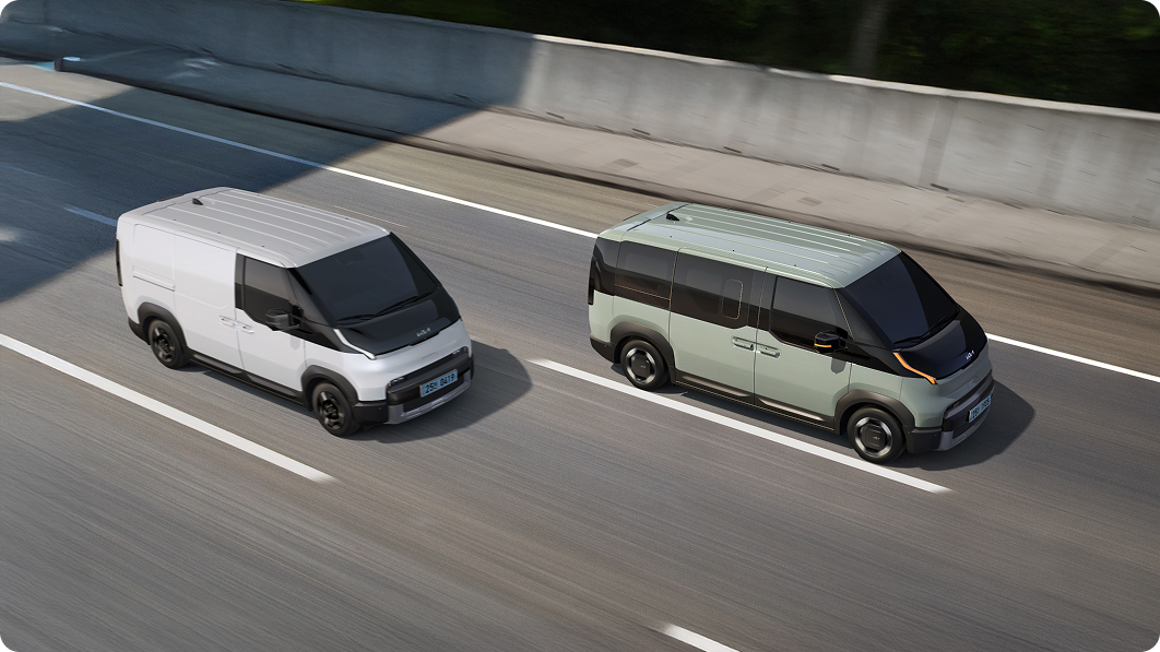 Two Kia PV5 vehicles driving side by side on a road