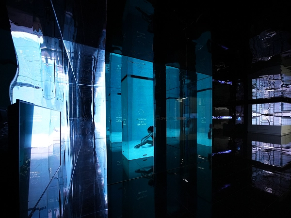 Exhibition space with blue-toned transparent panels and layered mirror reflections at the Gwangju Design Biennale.