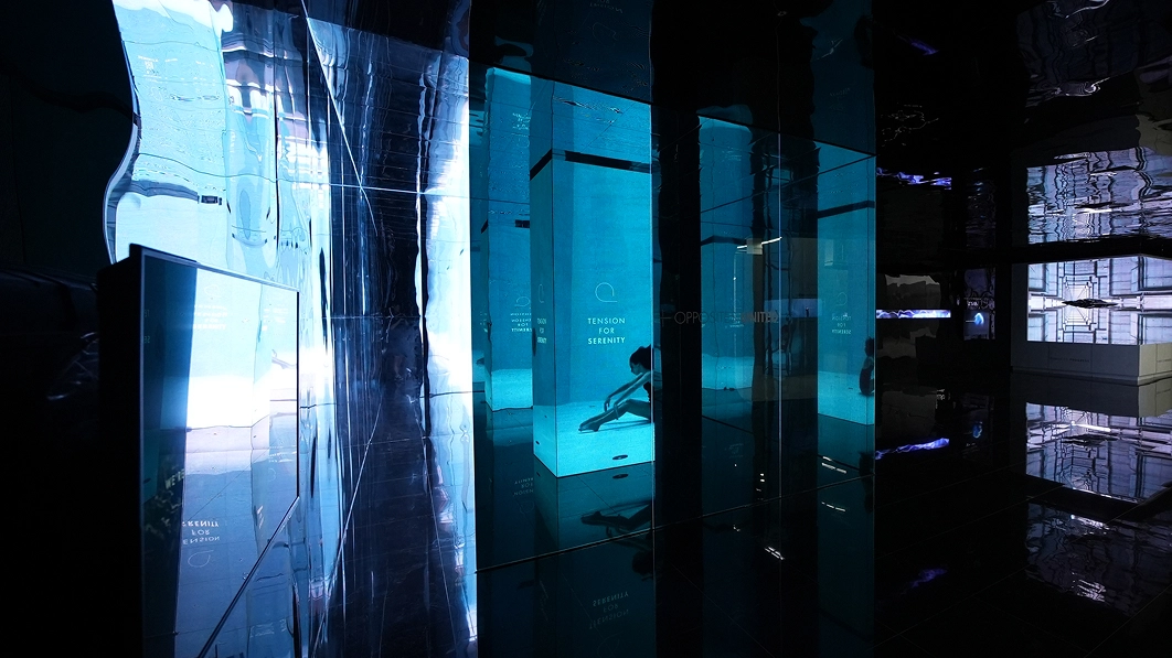 Exhibition space with blue-toned transparent panels and layered mirror reflections at the Gwangju Design Biennale.