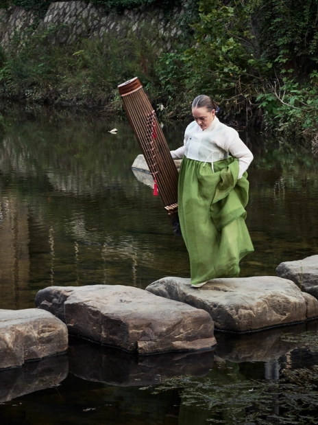 A musician performing on a rock beside a lake