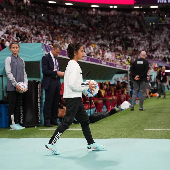 Ball kid entering the pitch holding a football at a FIFA stadium