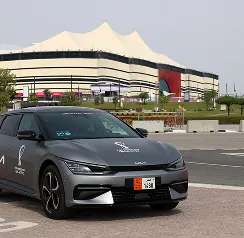 Kia electric vehicle parked in front of a Qatar World Cup stadium