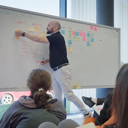 A Kia employee presenting ideas at a whiteboard covered with sticky notes during a team workshop