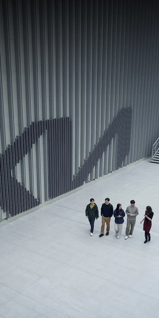 Kia employees walking together past a wall bearing the Kia logo