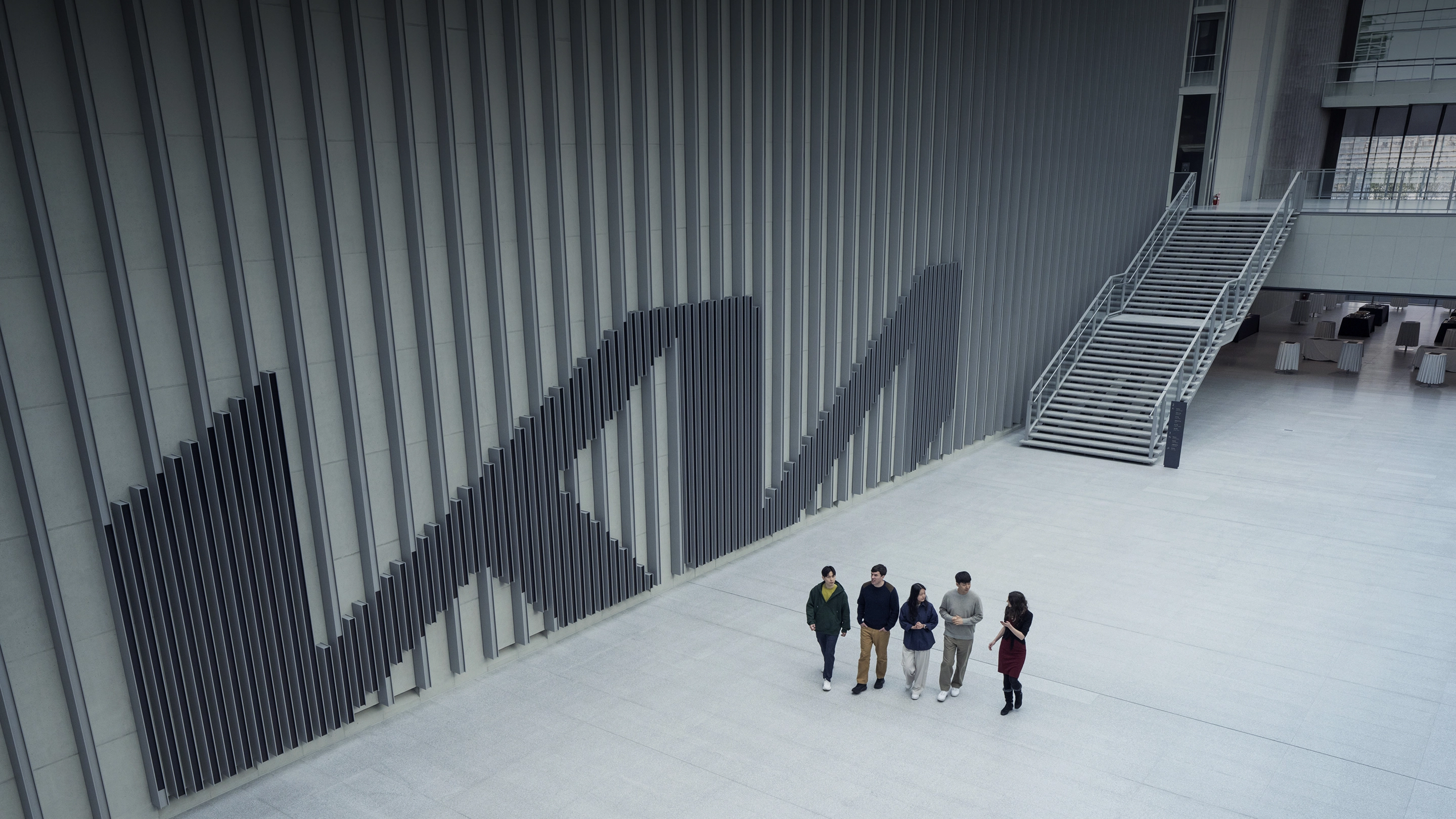 Kia employees walking together past a wall bearing the Kia logo