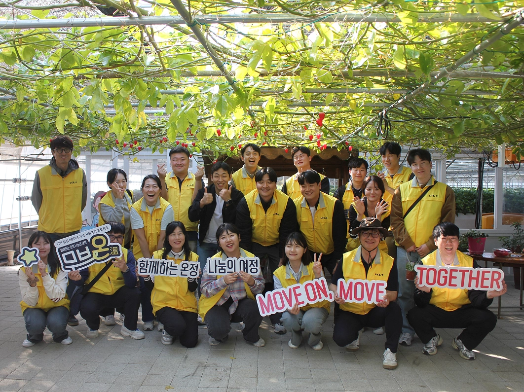 Kia employees in yellow vests posing for a group photo, holding placards reading 'MOVE ON, MOVE TOGETHER'