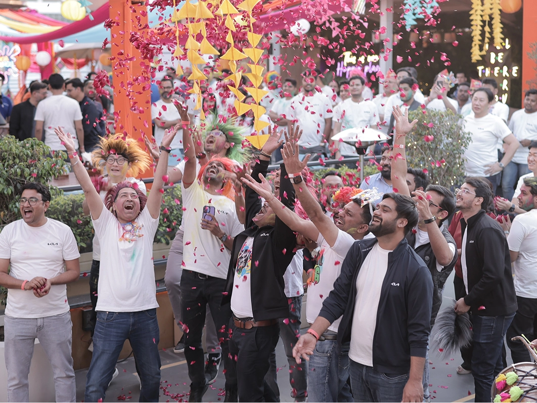 Kia India employees covered in colored powder, throwing petals and cheering at the Holi festival