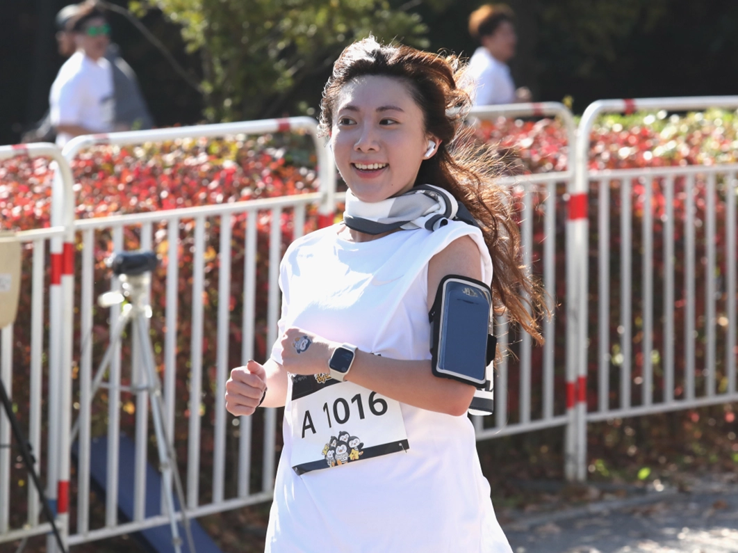 A Kia employee wearing a race bib smiling while running a marathon course