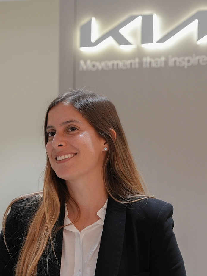 Image of Mariel from Kia Europe smiling in front of the Kia logo