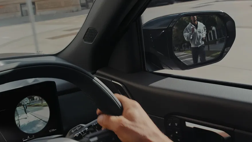 A driver checking for pedestrians via the side mirror and the Blind-Spot View Monitor (BVM) on the instrument cluster.