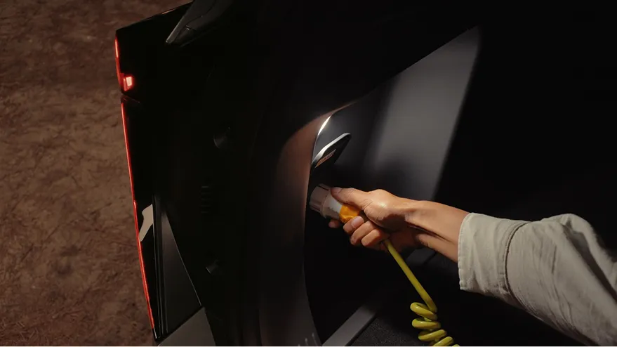 A driver connecting a power cable using the external Vehicle-to-Load (V2L) feature.