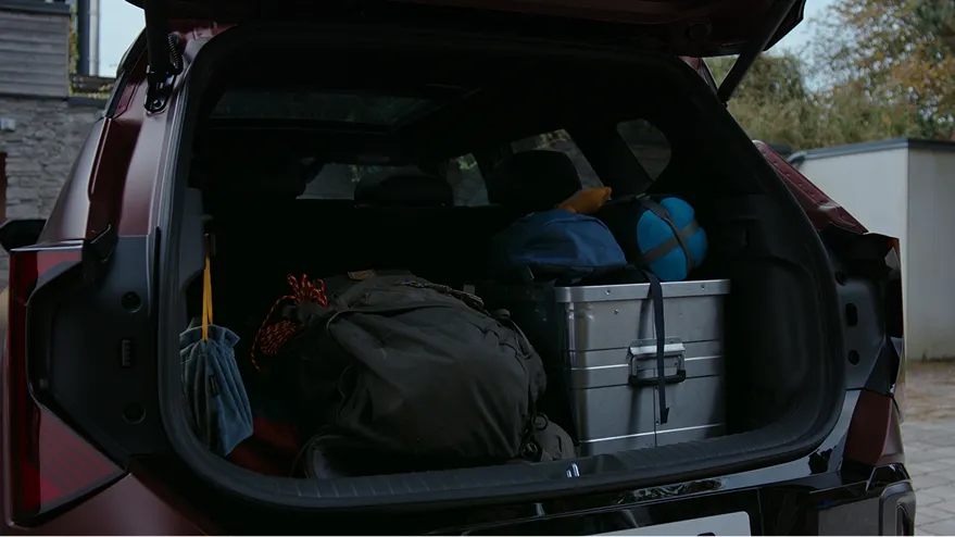 The Seltos cargo area loaded with camping gear and storage boxes..