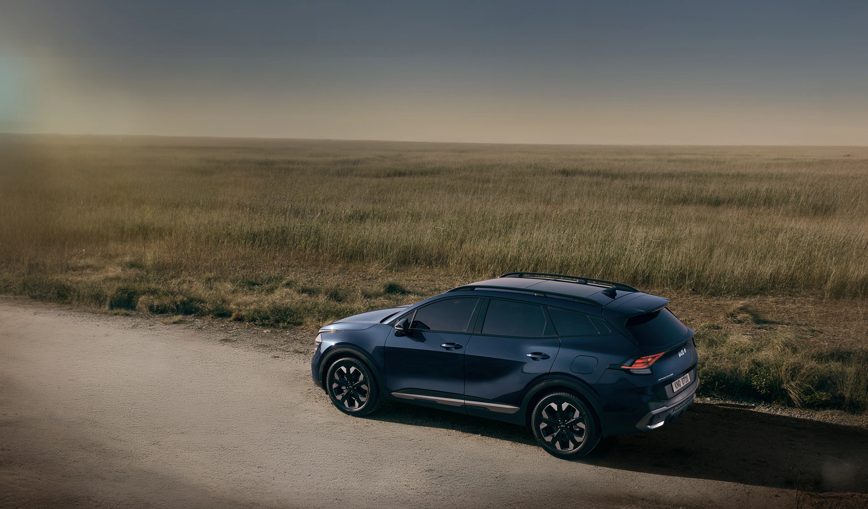 4세대 기아 스포티지가 갈대 밭이 있는 도로를 주행하는 모습