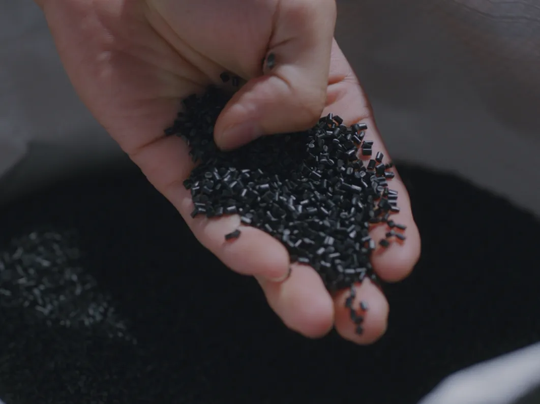 A close-up of recycled plastic pellets held in a hand
