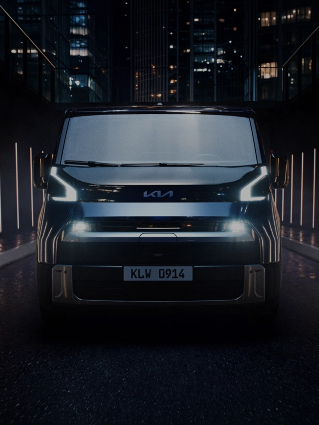 Front view of the Kia PV7 with its daytime running lights illuminated in a dark setting