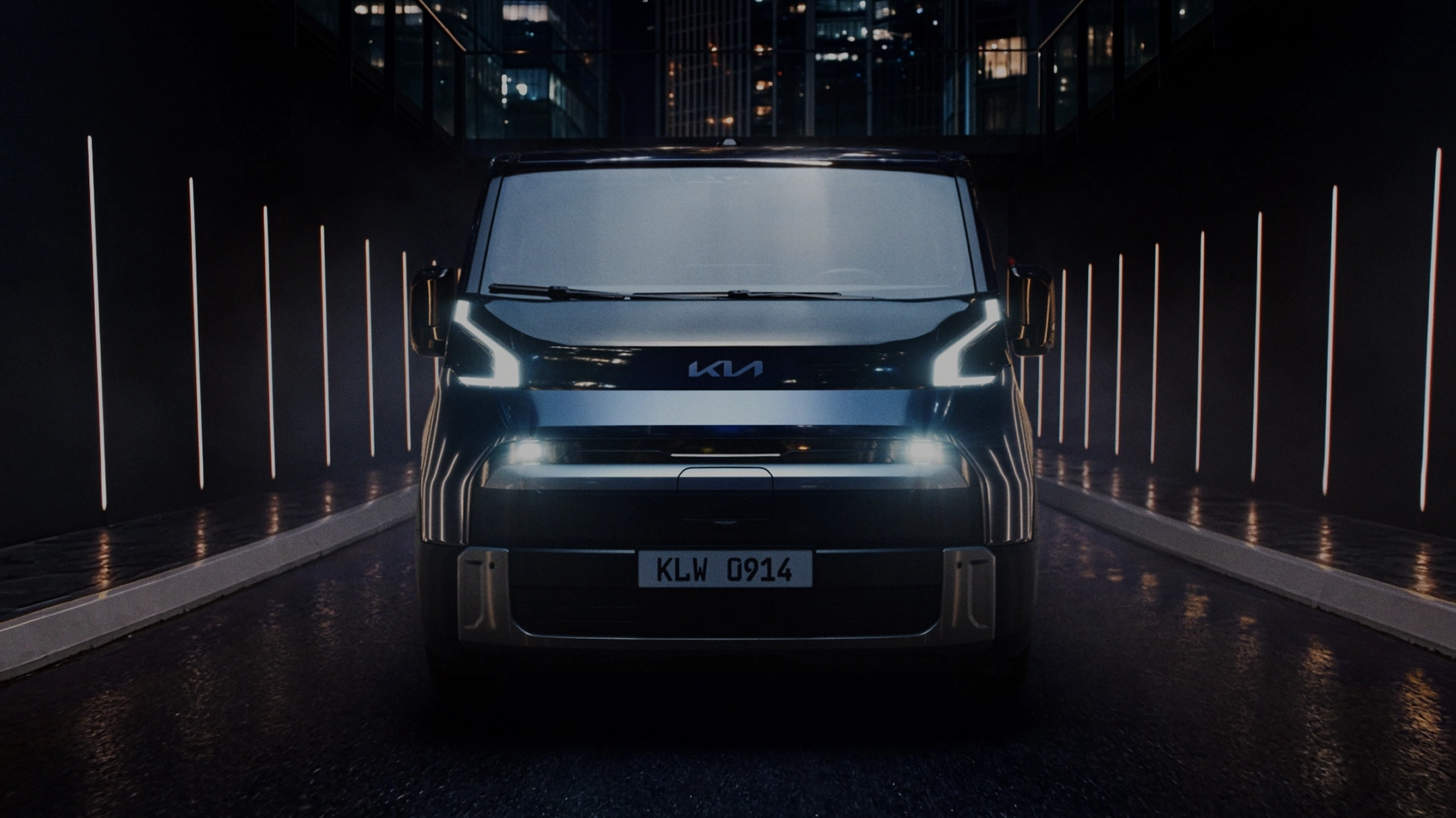Front view of the Kia PV7 with its daytime running lights illuminated in a dark setting
