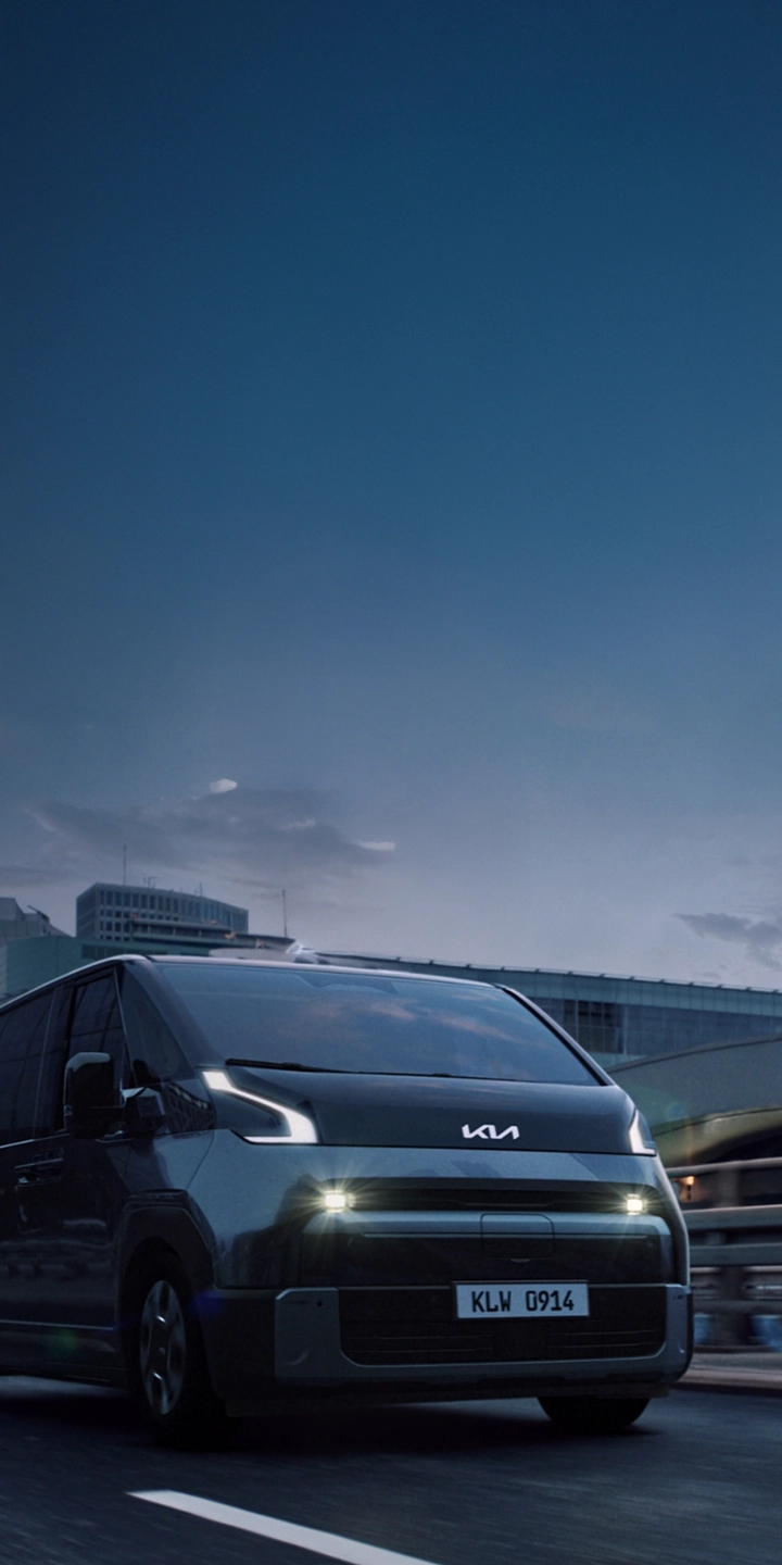 Front three-quarter view of the Kia PV7 driving on an urban road