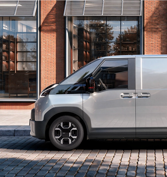 Side view of the Kia PV7 parked in front of a building